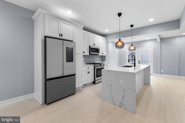 kitchen featuring a kitchen island with sink, white cabinets, sink, light hardwood / wood-style floors, and stainless steel appliances