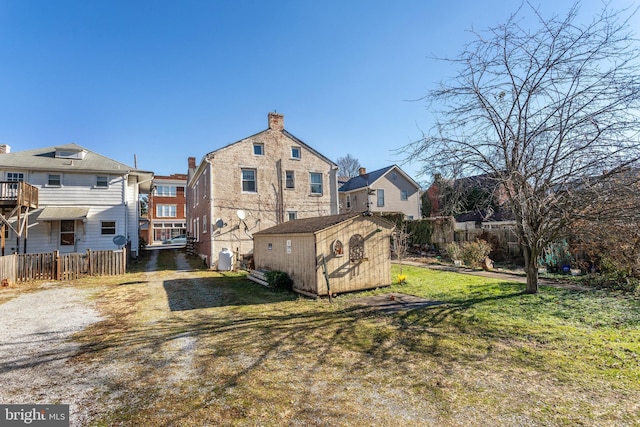 rear view of property with a yard and a storage unit