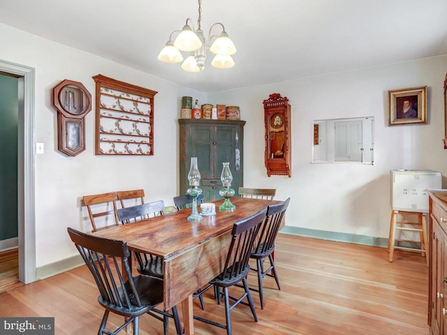 dining space with light hardwood / wood-style flooring and an inviting chandelier