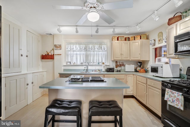 kitchen featuring a kitchen breakfast bar, track lighting, light hardwood / wood-style flooring, and black appliances