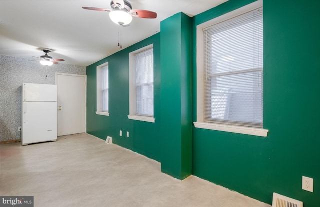 empty room with ceiling fan and a wealth of natural light