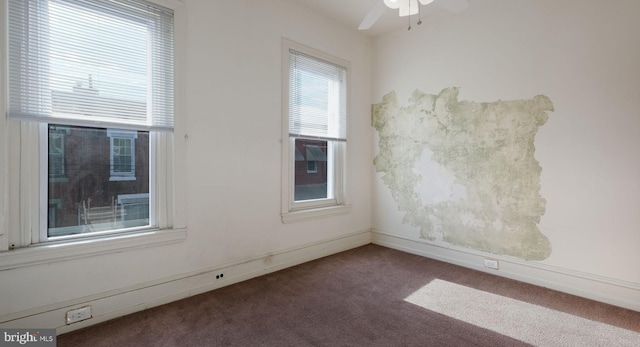 empty room with dark colored carpet and ceiling fan