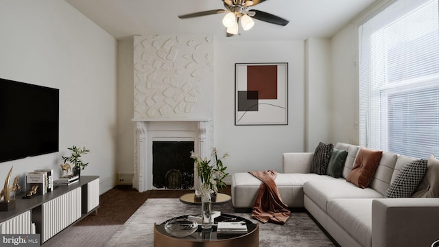 living room with dark colored carpet, a fireplace, and ceiling fan