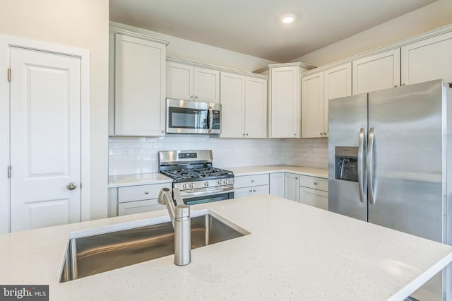 kitchen with decorative backsplash, stainless steel appliances, light stone counters, and sink