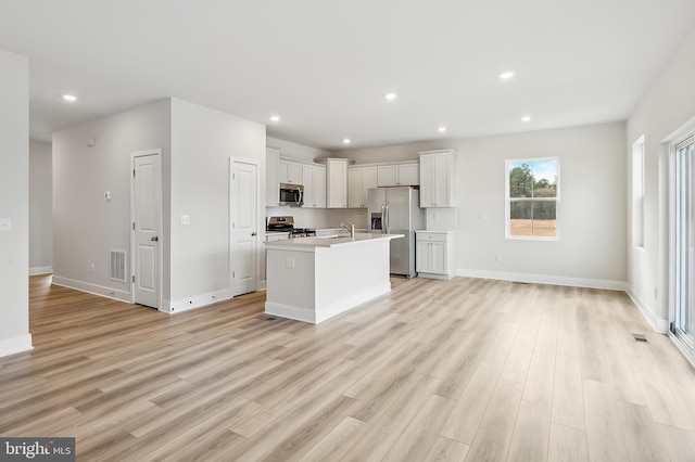 kitchen featuring a kitchen island with sink, sink, stainless steel appliances, and light hardwood / wood-style floors