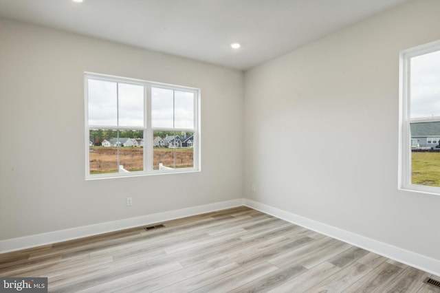 empty room with light hardwood / wood-style flooring and a healthy amount of sunlight