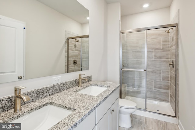 bathroom with vanity, a shower with shower door, and toilet