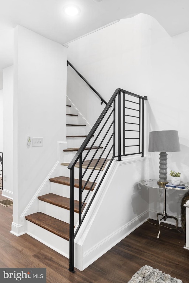 staircase with wood-type flooring and vaulted ceiling