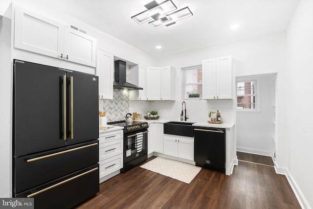 kitchen with black appliances, wall chimney exhaust hood, white cabinetry, and sink