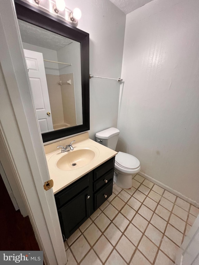 bathroom with tile patterned floors, a shower, a textured ceiling, toilet, and vanity