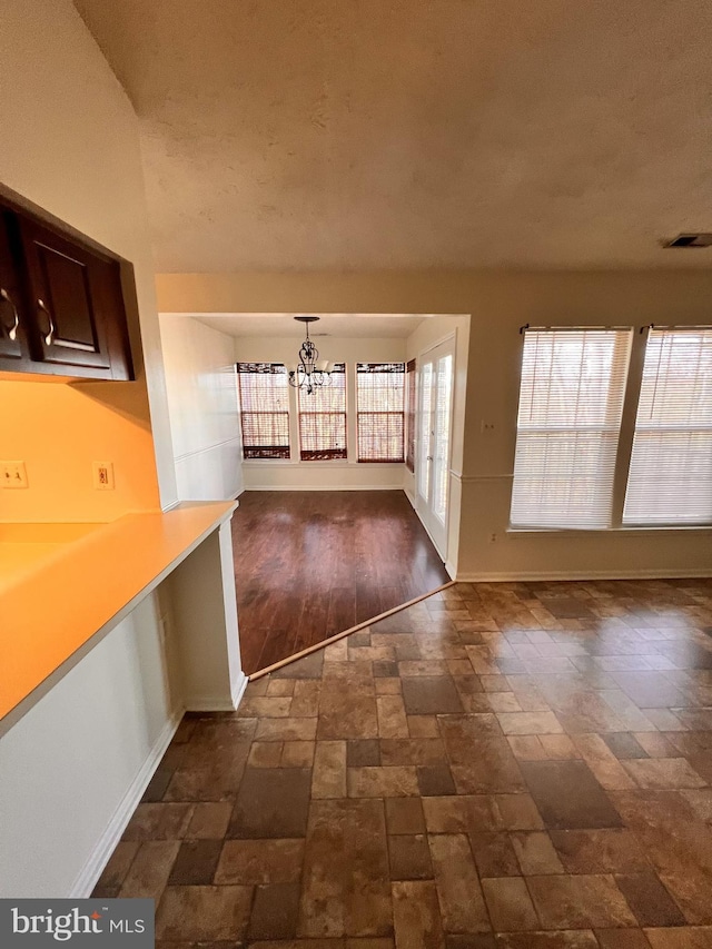 unfurnished dining area with dark wood-type flooring and an inviting chandelier