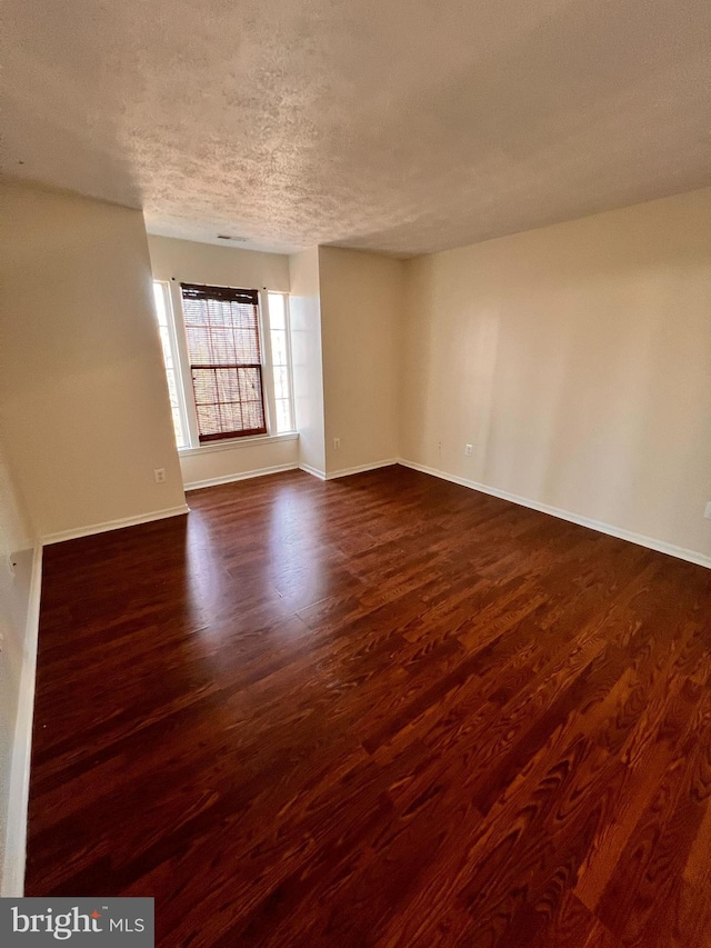 unfurnished room featuring dark wood-type flooring and a textured ceiling