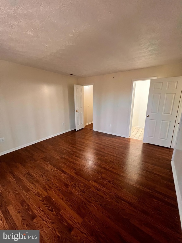 spare room with dark wood-type flooring and a textured ceiling