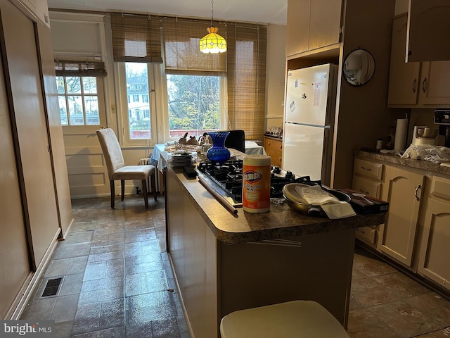 kitchen featuring a center island, white fridge, and pendant lighting