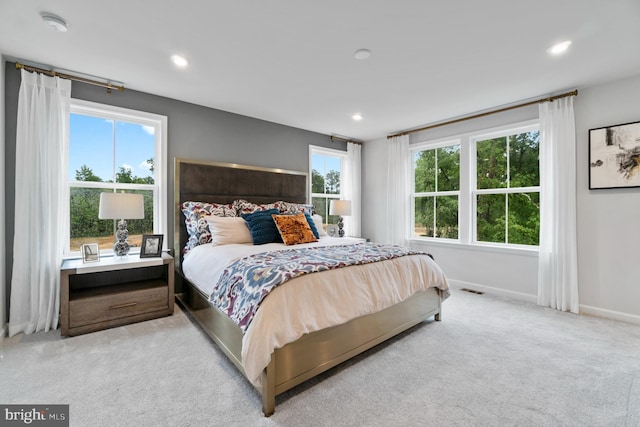 bedroom with light colored carpet and multiple windows