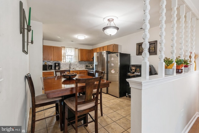 kitchen featuring kitchen peninsula, decorative backsplash, sink, light tile patterned flooring, and stainless steel appliances