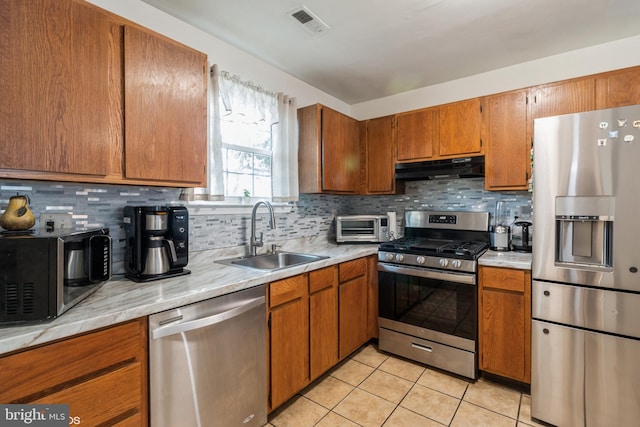 kitchen with tasteful backsplash, light tile patterned floors, appliances with stainless steel finishes, and sink