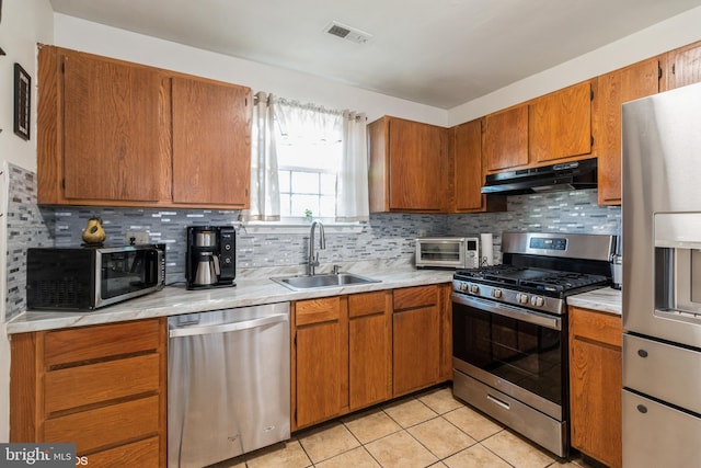 kitchen with light tile patterned floors, appliances with stainless steel finishes, decorative backsplash, and sink