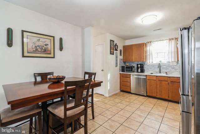 kitchen featuring light tile patterned floors, appliances with stainless steel finishes, tasteful backsplash, and sink