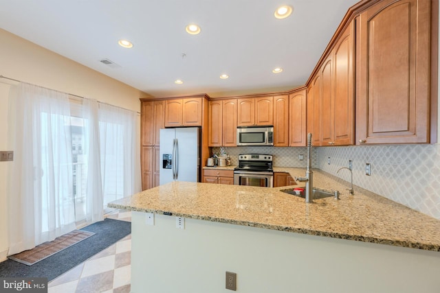 kitchen with kitchen peninsula, light stone countertops, and stainless steel appliances