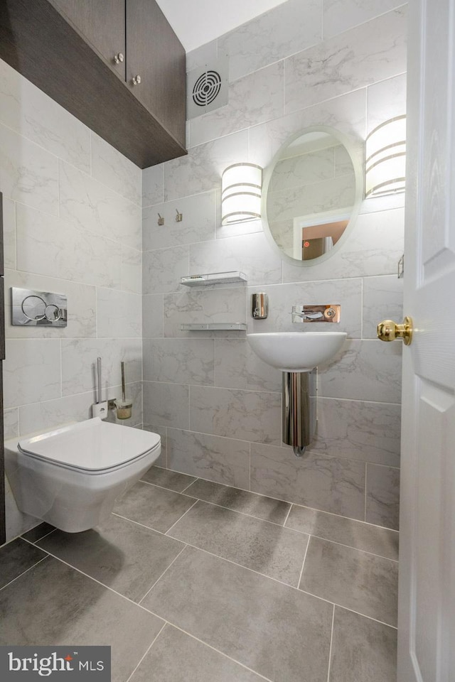 bathroom with tile patterned floors, toilet, and tile walls