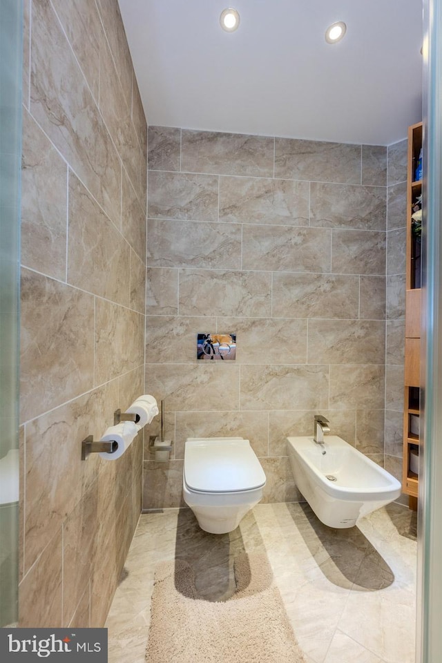 bathroom featuring tile patterned flooring, a bidet, toilet, and tile walls