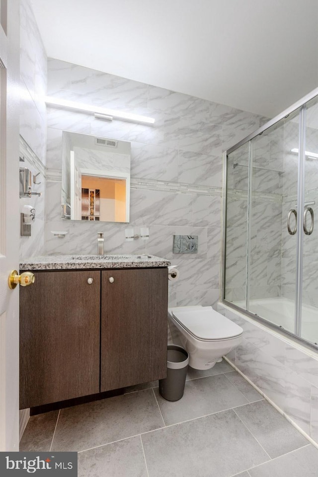 full bathroom with tile patterned flooring, enclosed tub / shower combo, and tile walls