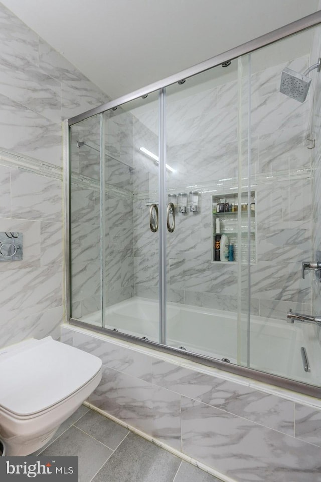 bathroom with shower / bath combination with glass door, tile patterned flooring, and toilet