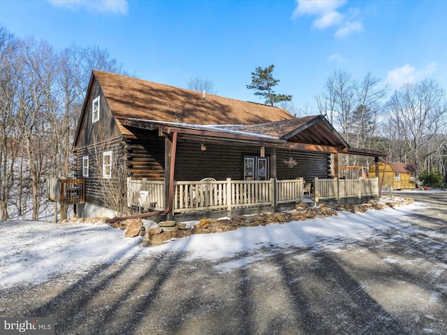 cabin featuring log exterior and a porch