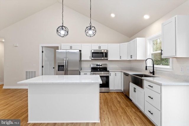 kitchen with pendant lighting, a center island, white cabinets, light hardwood / wood-style flooring, and appliances with stainless steel finishes