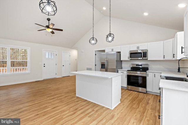 kitchen with appliances with stainless steel finishes, light hardwood / wood-style floors, a kitchen island, and hanging light fixtures