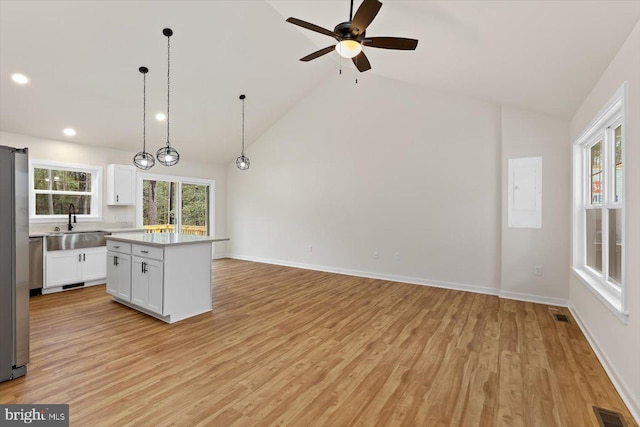 kitchen with white cabinetry, high vaulted ceiling, light hardwood / wood-style flooring, a kitchen island, and hanging light fixtures