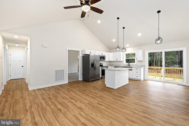 kitchen with a center island, stainless steel appliances, high vaulted ceiling, and light hardwood / wood-style floors