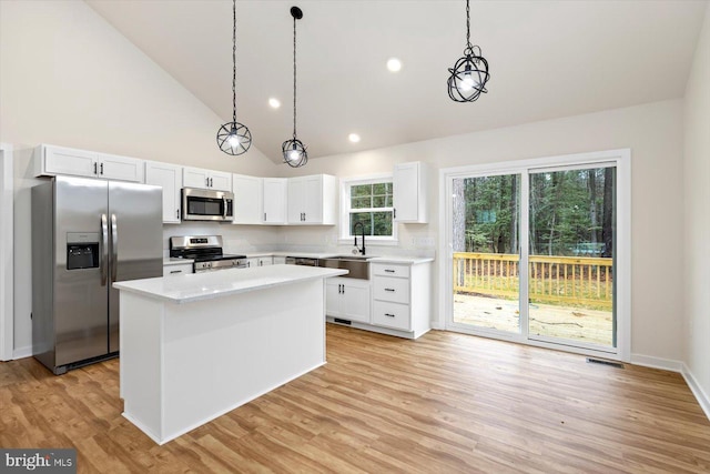 kitchen featuring pendant lighting, a center island, white cabinets, and stainless steel appliances