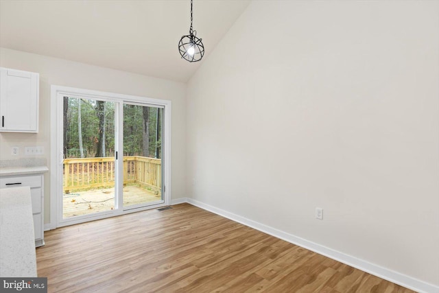 unfurnished dining area featuring a chandelier, light hardwood / wood-style floors, and high vaulted ceiling