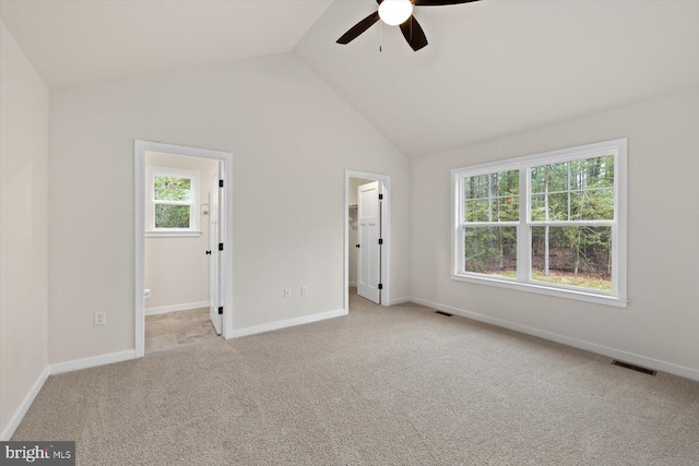 unfurnished bedroom featuring multiple windows, a spacious closet, light carpet, and lofted ceiling