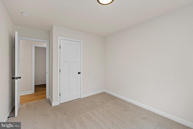 unfurnished bedroom featuring light carpet and a closet