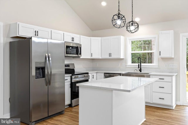 kitchen with white cabinets, a kitchen island, appliances with stainless steel finishes, and vaulted ceiling