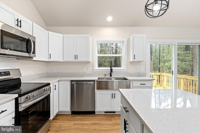 kitchen with white cabinetry, sink, stainless steel appliances, and lofted ceiling