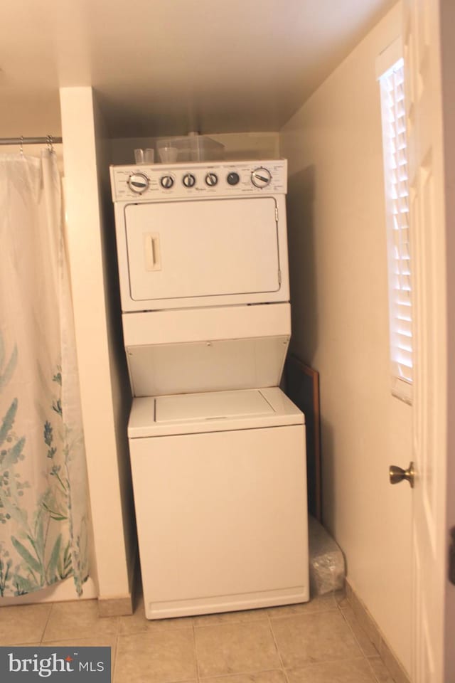 laundry area with light tile patterned flooring and stacked washer / dryer