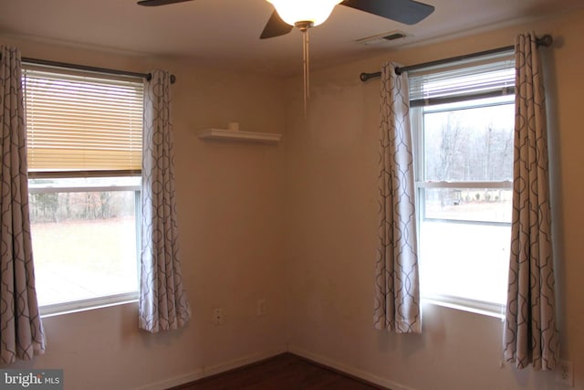 empty room featuring plenty of natural light, dark wood-type flooring, and ceiling fan