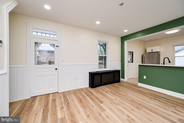 foyer entrance with radiator, sink, and light wood-type flooring