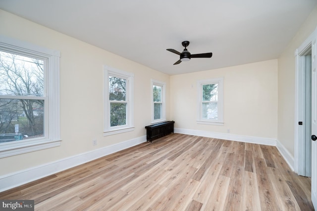 unfurnished living room featuring ceiling fan, radiator heating unit, and light hardwood / wood-style floors