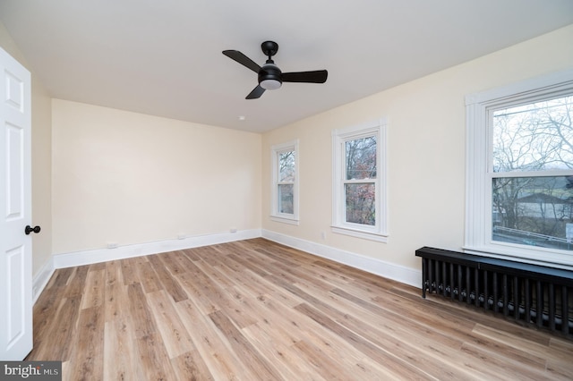 spare room with ceiling fan, light hardwood / wood-style floors, and radiator heating unit