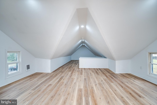 bonus room featuring light wood-type flooring, vaulted ceiling, and a healthy amount of sunlight