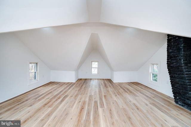 additional living space featuring lofted ceiling, light hardwood / wood-style flooring, and plenty of natural light