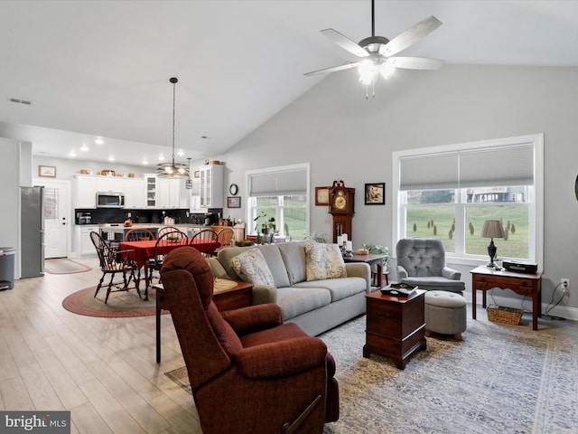 living room featuring ceiling fan, a healthy amount of sunlight, high vaulted ceiling, and light hardwood / wood-style flooring