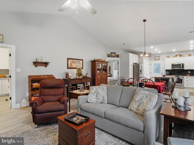 living room with light hardwood / wood-style floors, high vaulted ceiling, and ceiling fan