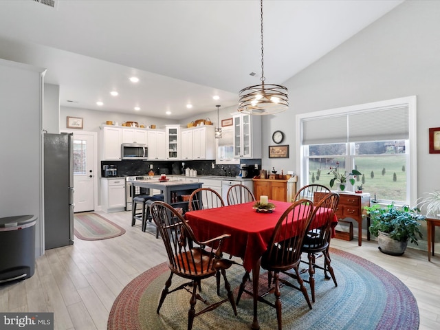 dining room with light hardwood / wood-style floors and vaulted ceiling