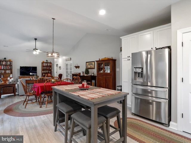 kitchen featuring ceiling fan, stainless steel fridge with ice dispenser, vaulted ceiling, white cabinets, and light wood-type flooring